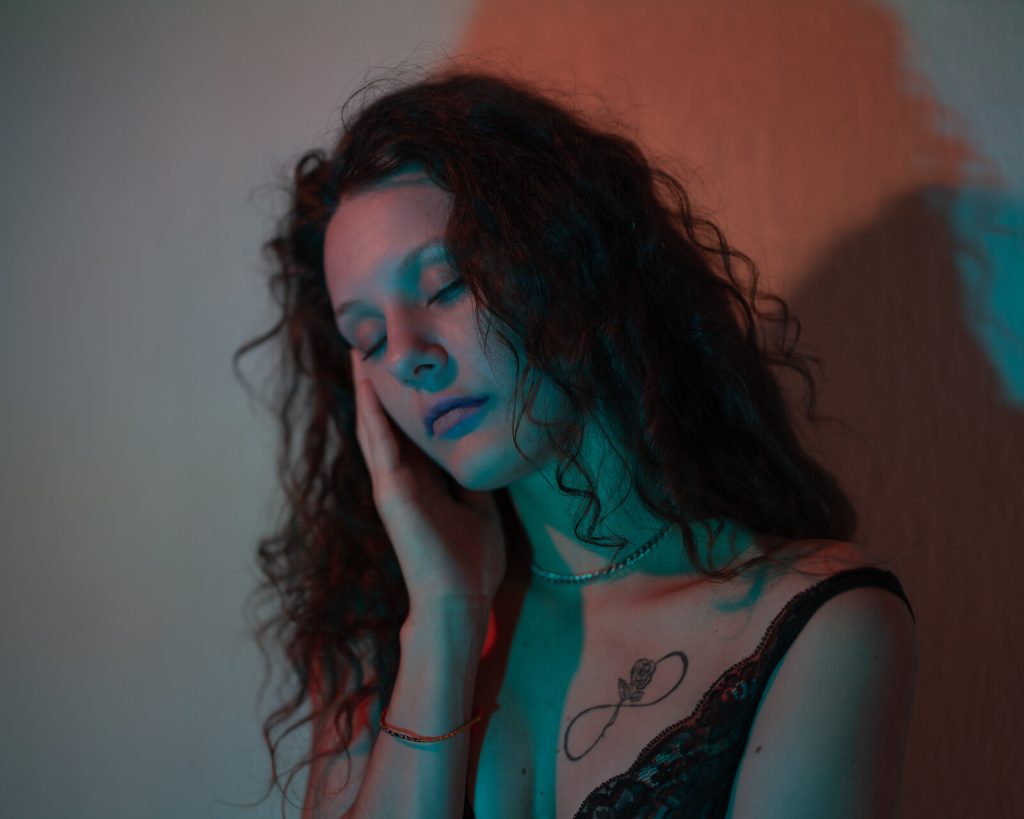 Portrait de Lili, regard baissé dans une lumière colorée